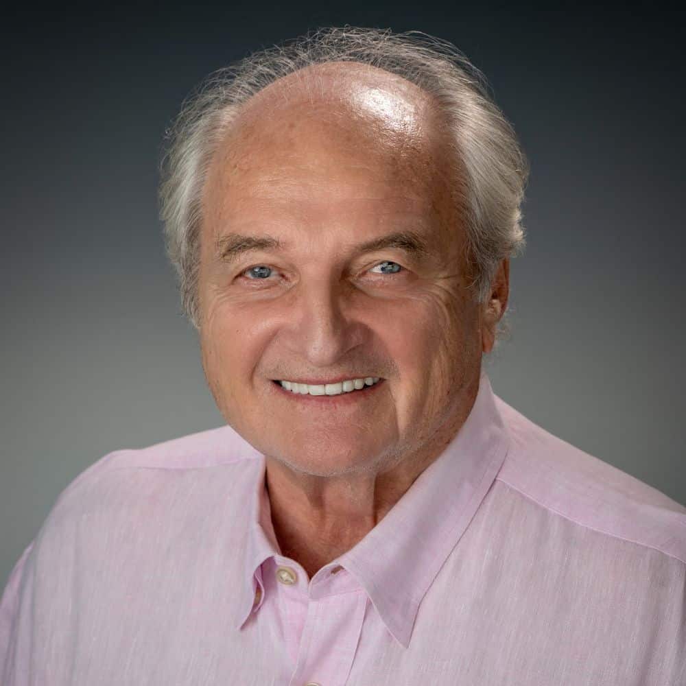 Friendly man smiling in professional headshot, wearing a pink shirt for business, portrait of a mature business leader.