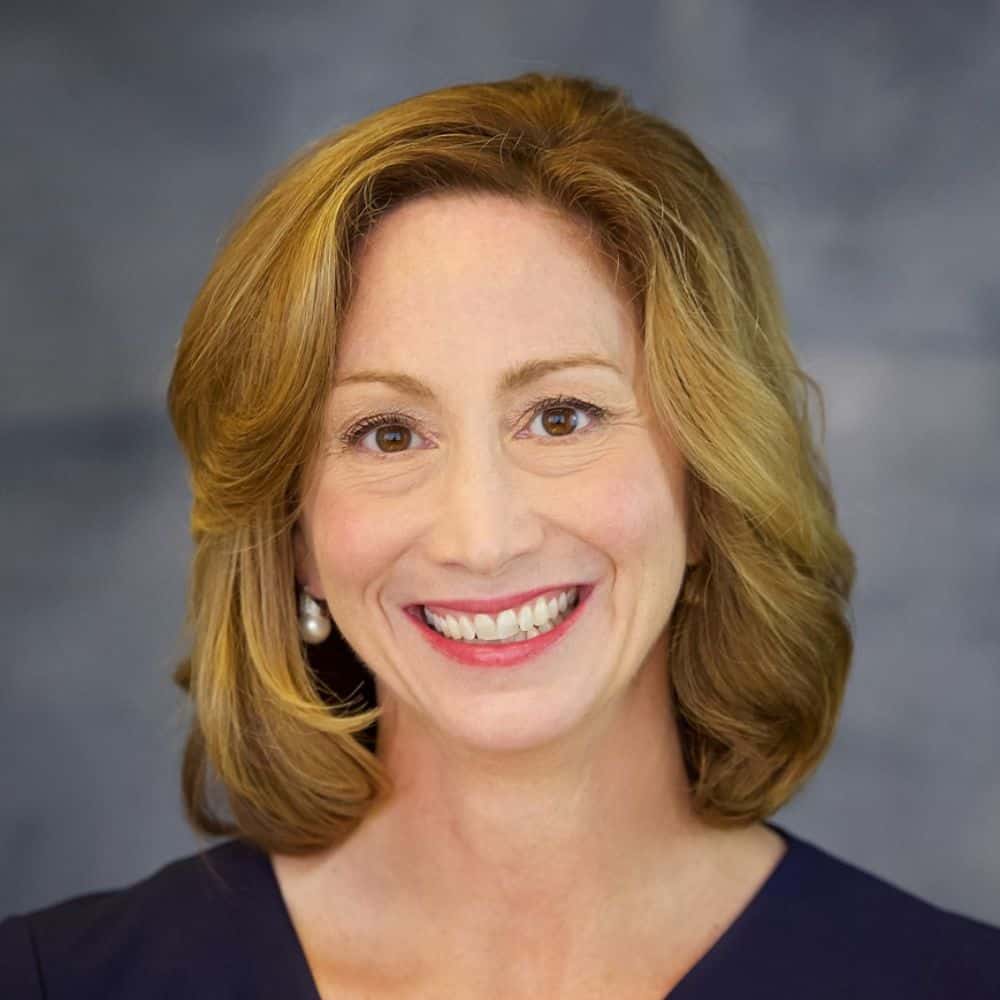 Friendly professional woman with red hair smiling, business headshot, confident expression, Carter.
