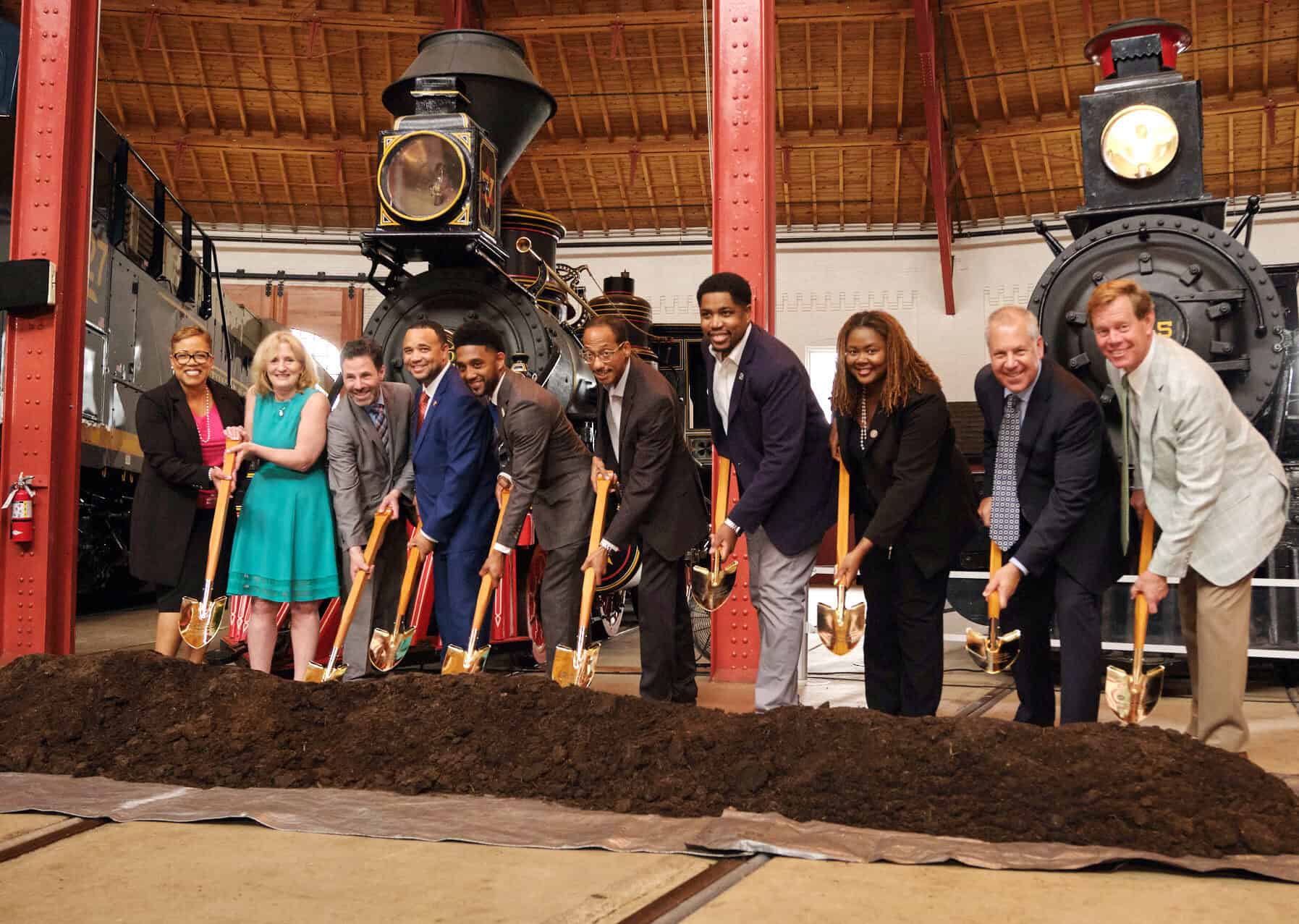 Historic train station groundbreaking ceremony for Carter partner, B&O Railroad Museum, with diverse professionals shoveling dirt.