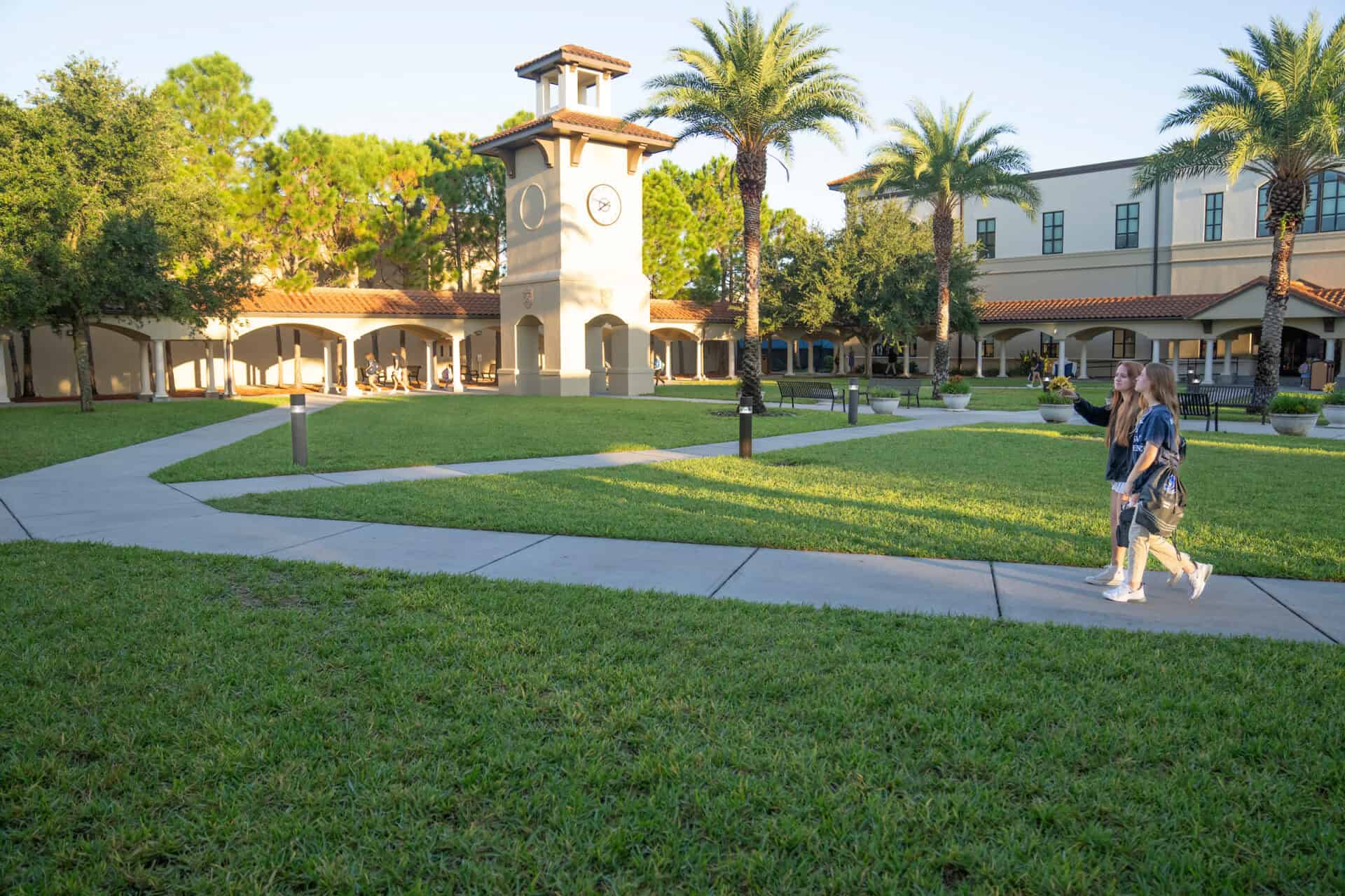 Photo of Berkeley Preparatory School, a Carter partner - Lush green grass surrounding school campus with walking paths, palm trees, and a central clock tower.