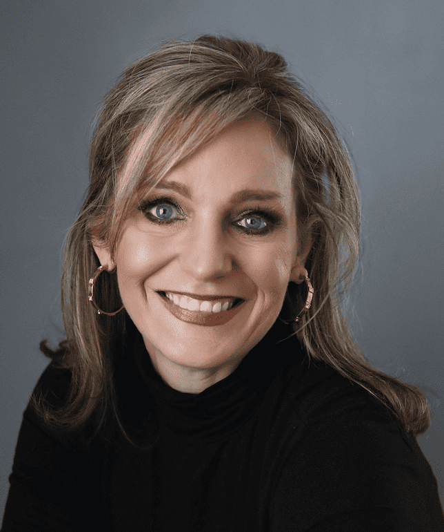 Elegant smiling woman with blonde hair and blue eyes, wearing black turtleneck and hoop earrings, portrait for professional headshot.