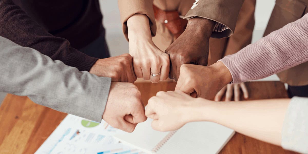Diverse-team-fist-bump-for-collaboration-in-office-setting.