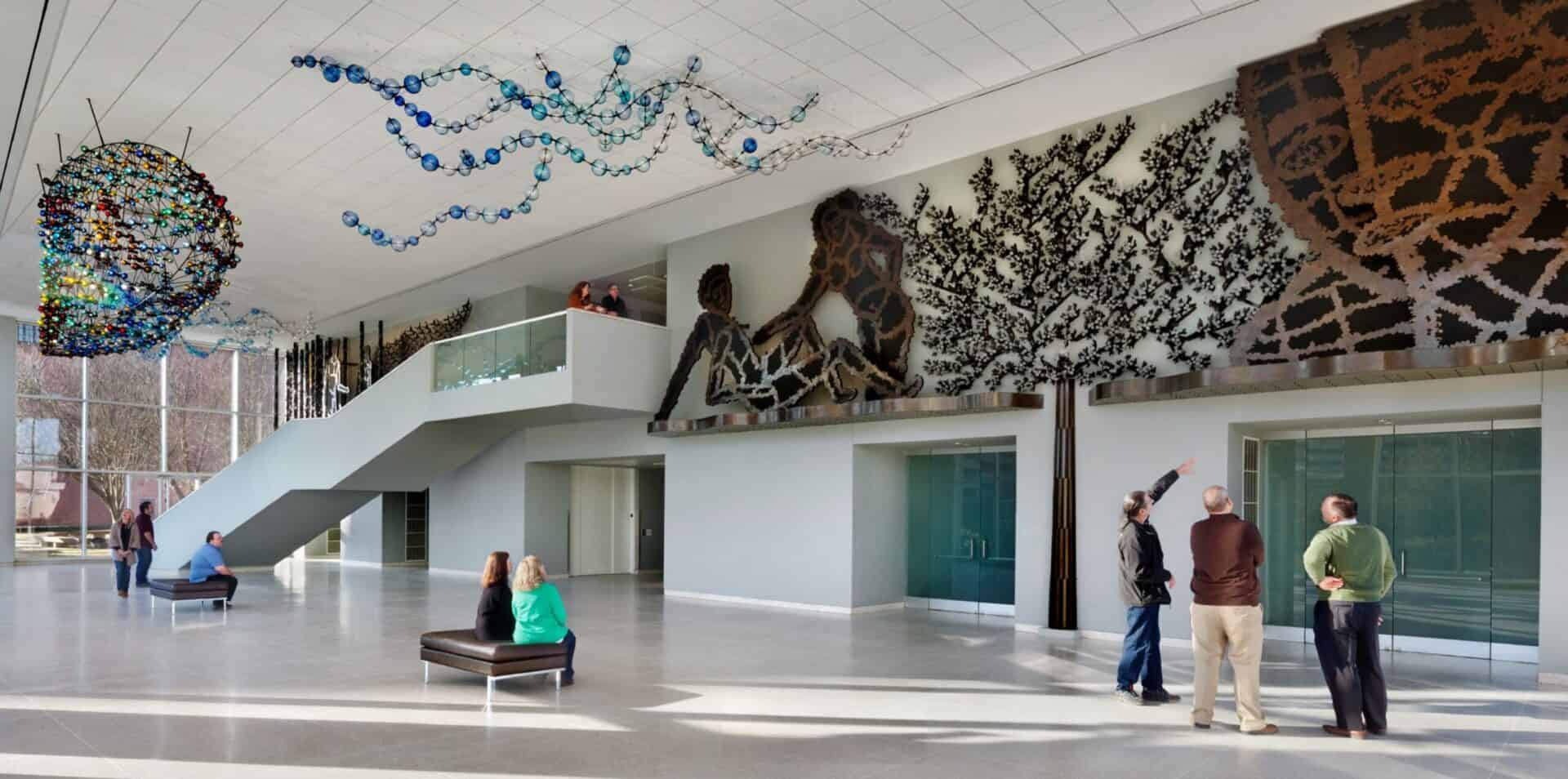 Vibrant modern art installation in a spacious museum lobby with people enjoying and discussing the artwork at the Knoxville Museum of Art, a Carter partner.