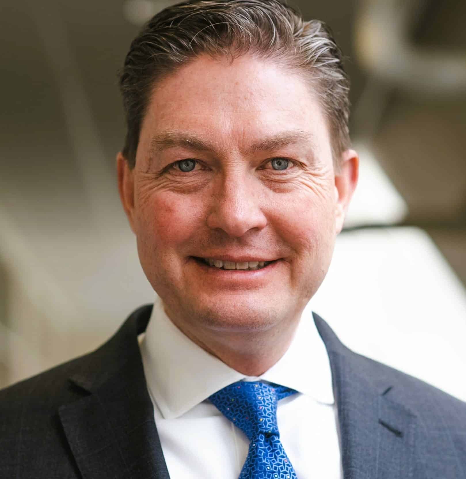 Professional man in business attire smiling, showcasing confidence and approach ability.