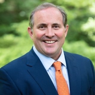 Professional portrait of a man in a suit outdoors, emphasizing leadership and business expertise.