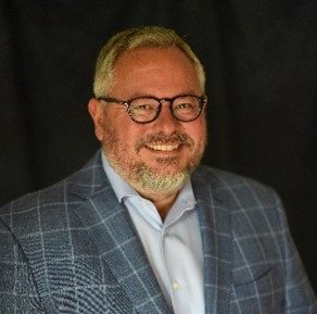 Professional man in glasses and a checkered suit smiling for headshot.