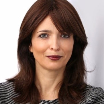 Professional head shot of woman with dark brown hair in a black and gray top.